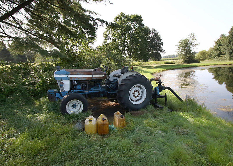 Tractor and water jugs parked next to an irrigation pond